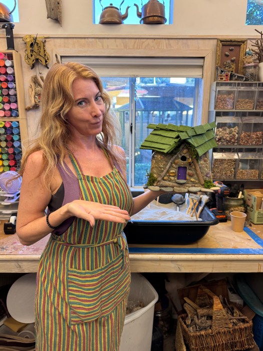 Blonde woman stands with her fairy house